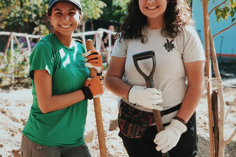 Two smiling young volunteers with spades at a community project